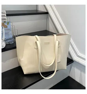 Chic cream-white leather tote bag with gold lettering displayed on black steps