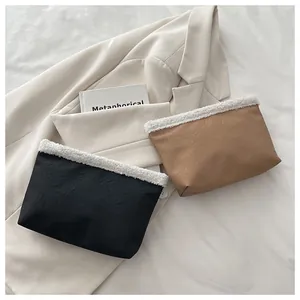 Dettaglio di pochette in pelle minimaliste con bordo in peluche nero e marrone