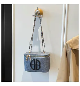 Détail du sac bandoulière en feutre bleu-gris avec fermetures éclair dorées et chaîne