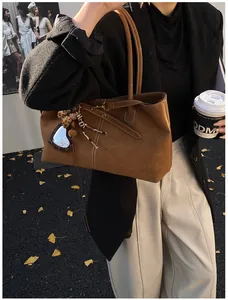 Close-up of retro brown suede tote bag with leopard heart mirror and plush charm detail