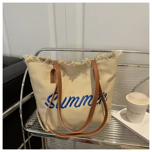 Détail du sac cabas en toile avec broderie Summer, bords frangés et anses en cuir
