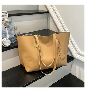 Detail of light brown leather tote bag showing shoulder straps and fashion text print