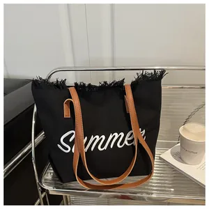 Détail du cabas en toile noire avec broderie Summer et franges sur fond minimaliste
