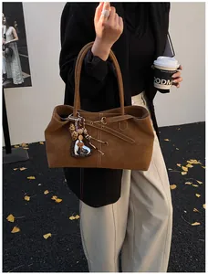 Brown matte leather tote bag with heart and leopard print charms in an autumn outdoor setting