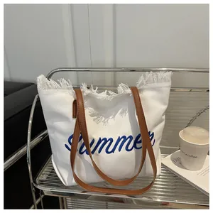 Détail du sac cabas en toile blanche avec broderie Summer bleue et bords à franges