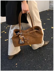 Brown suede tote bag with leopard heart charm and ginkgo leaves on autumn pavement