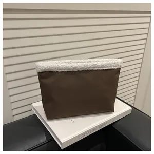 Dettaglio della pochette in pelle marrone con bordo in sherpa bianco e design minimalista