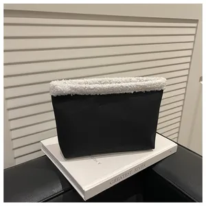 Dettaglio pochette in pelle nera con bordo in pelliccia sintetica bianca e stile chic