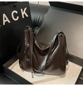 Detail of dark brown leather hobo bag with tassel zipper in a premium gift box setup