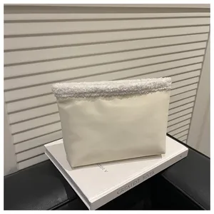 Dettaglio della borsa in ecopelle crema con bordo in peluche bianco sopra un libro