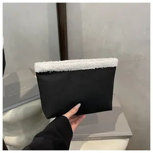 Dettaglio pochette nera con bordo in ecopelliccia bianca e design a contrasto puro
