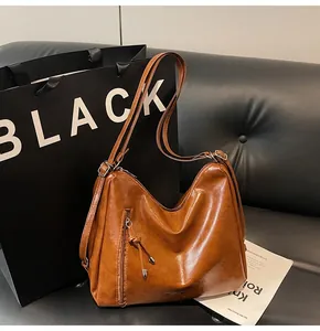Detailed close-up of brown leather tote bag with vertical zipper and fashion branding