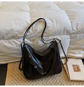 Close-up of deep brown hobo bag featuring a vertical zipper and silver metal buckle