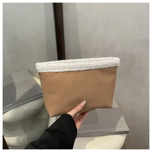 Dettaglio della pochette in pelle kaki con bordo in sherpa bianco in mano