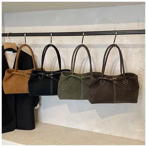 Detail of minimalist suede tote bags in camel, black, green and brown with decorative stitching