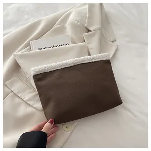 Dettaglio pochette in ecopelle marrone con bordo in peluche su un blazer beige chiaro