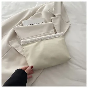 Dettaglio della pochette in pelle beige con bordo in ecopelliccia bianca e vista della capienza