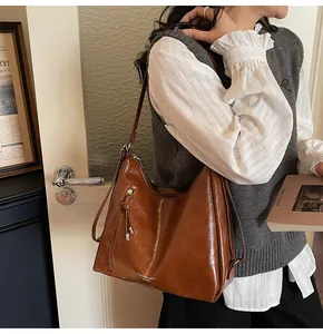 Detail view of retro brown leather tote with metal tassel and zipper accents