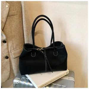 Detailed close-up of a black leather tote bag featuring fine white contrast stitching accents