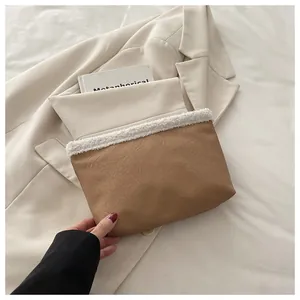 Dettaglio del bordo in peluche su una pochette in pelle marrone con un libro