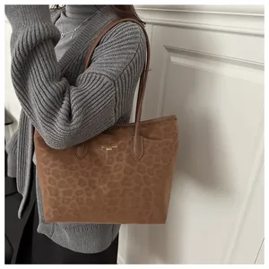 Lifestyle shot of a leopard print suede tote bag on a woman wearing a grey sweater