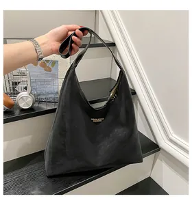Close-up of matte black tote bag with gold lettering and soft textured synthetic leather
