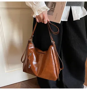 Detail of vintage brown oil wax leather hobo bag with tassel zippers and adjustable strap
