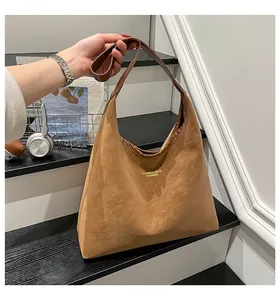 Detail of matte brown oversized tote bag with gold lettering and soft suede texture