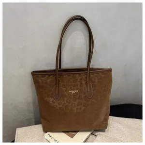 Detail of leopard print tote bag with gold brand logo and slim leather handles