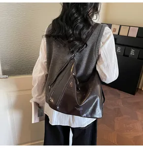 Detail of deep brown glossy leather tote bag showing smooth texture and logo text