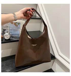 Detail of a deep brown faux leather tote bag with elegant golden fashion lettering