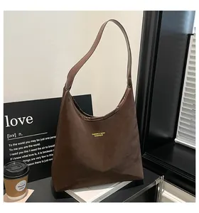 Detailed close-up of dark brown leather texture and golden logo on fashion tote bag