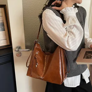 Brown large capacity leather tote bag with vintage glossy finish and tassel zipper detail