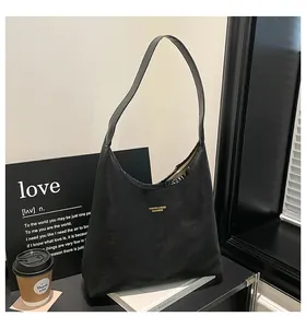 Detailed close-up of a matte black shoulder bag with a gold logo for commuting