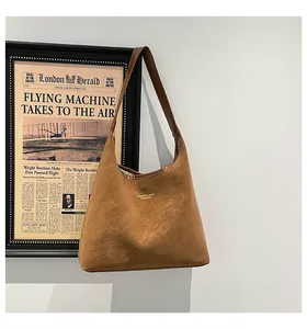Detail of a brown matte leather hobo bag with gold logo text on a vintage background