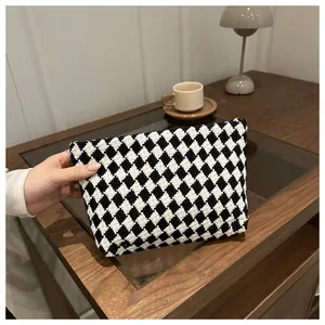 Close-up of black and white checkerboard knit clutch with metal zipper detail