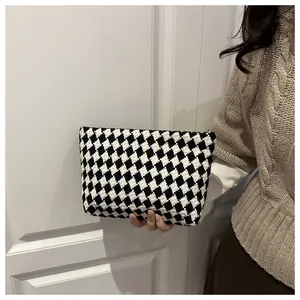 Detail of a chic black and white checkered knitted clutch with a premium golden zipper