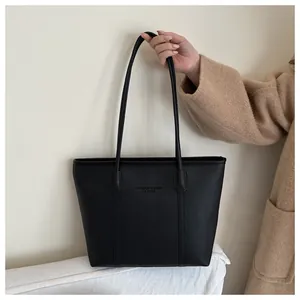 Close-up of black lychee grain leather tote with embossed fashion lettering and slim strap