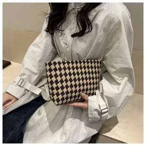 Detailed view of luxury checkered tweed clutch bag with elegant black and beige diamonds