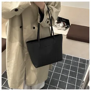 Detail of minimalist black pebbled leather tote bag styled in a modern office setting
