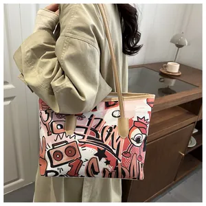 Dettaglio della borsa tote in tela con graffiti rosa e tracolla in pelle marrone casa