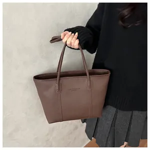 Detail of dark brown lychee leather tote bag with embossed fashion text for daily commuting