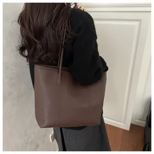Close-up of large dark brown leather tote bag with pebble texture and fine stitching detail