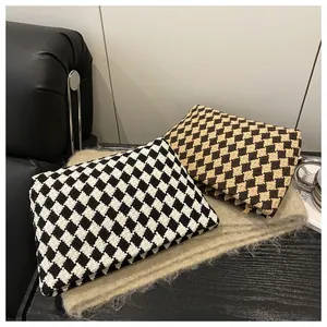 Detail of woven lattice clutch bags in black-white and coffee tones with metal zippers
