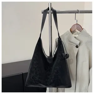Dettaglio della borsa tote in pelle cerata nera con cuciture a contrasto e nappa in pelle