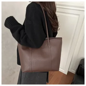 Detail of dark brown pebble leather tote bag shown on model for size and capacity scale