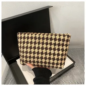 Close-up of the textured brown and beige woven geometric pattern on a luxury clutch bag