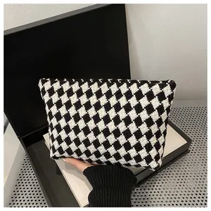 Detailed view of luxury houndstooth clutch bag with black and white woven pattern