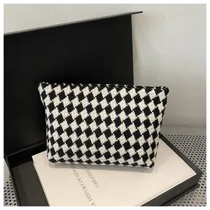 Detailed view of houndstooth weave texture on luxury clutch bag in a gift box