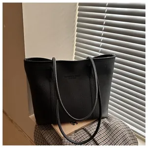 Close-up of litchi textured black leather tote bag with debossed fashion brand lettering